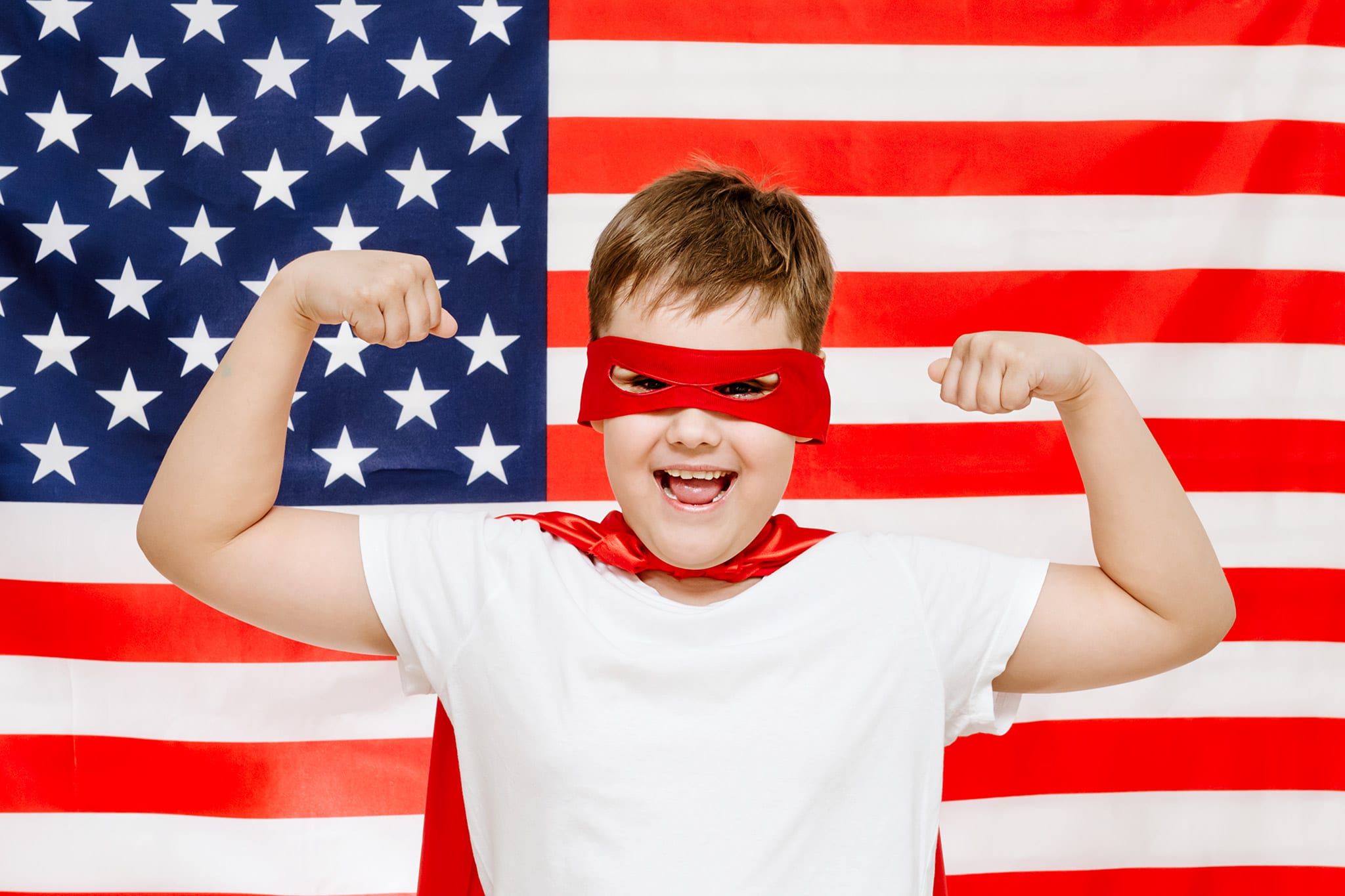 Boy in a superhero outfit in front of the United States flag